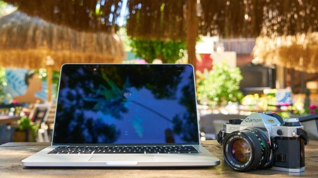 laptop and a camera on a wooden table at a beach resort.