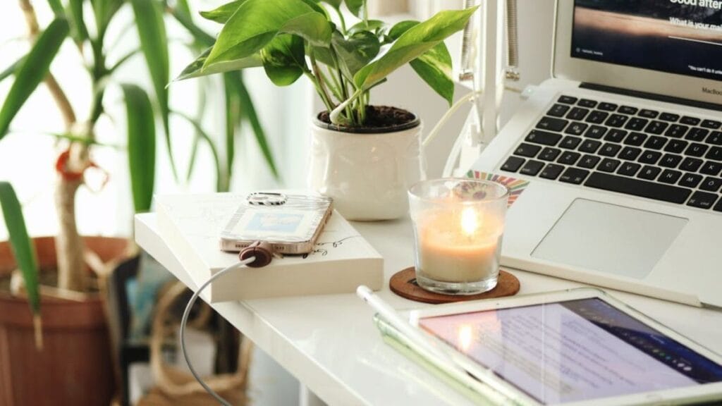 example of designing your environment that promotes work with natural light, laptop, candle, phone and charger