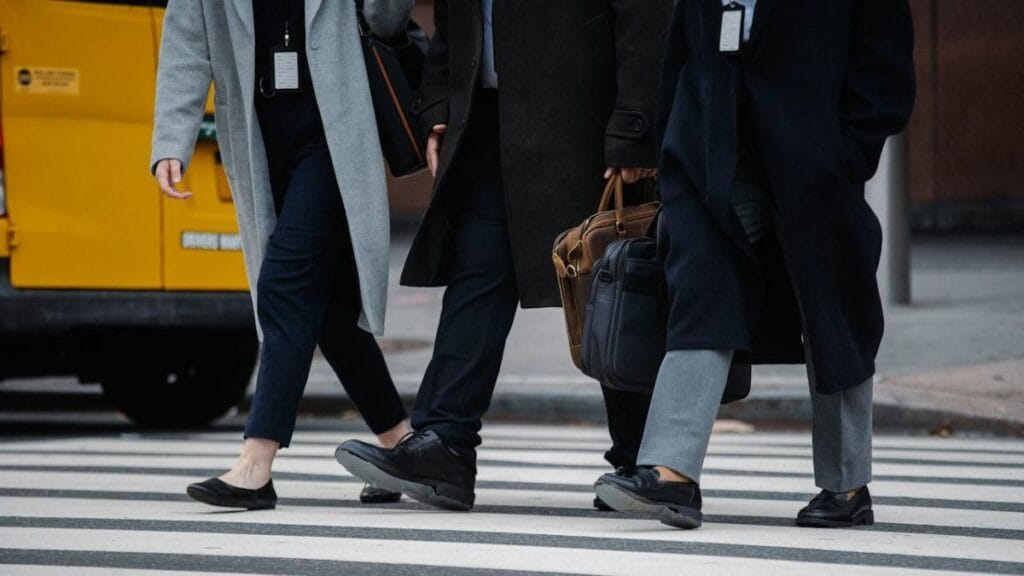 People in business attire crossing the street at a zebra crossing