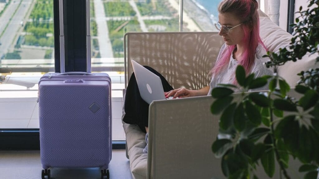 a digital nomad working on her laptop at an airport lounge on her way to nomad destination