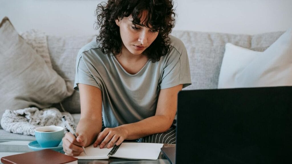 woman making notes while learning digital skills on her laptop