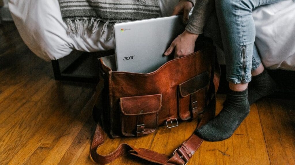 woman packing her laptop in leather travel bag.