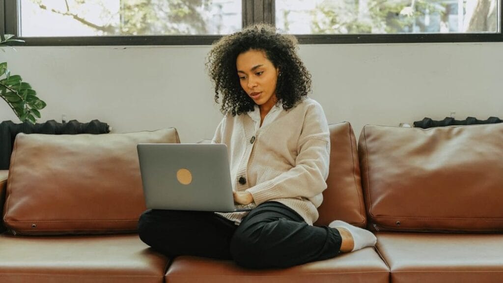 woman studying on her laptop sitting on a couch in her home