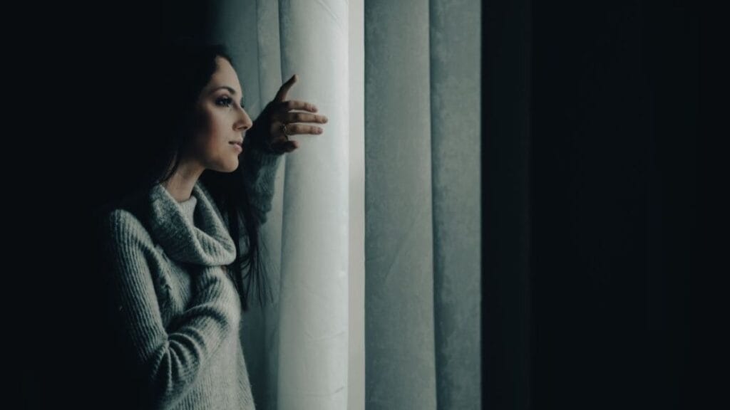 woman thinking about designing a life while looking outside from a window.