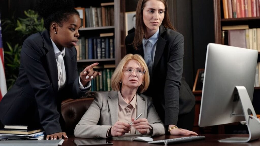 lawyers discussing while looking at a computer screen.