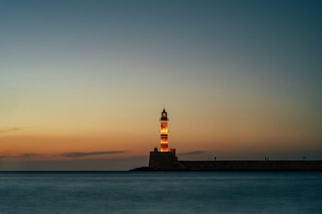 A calm lighthouse at sunset guiding the shoreline, symbolizing clarity, direction, and grounded guidance.