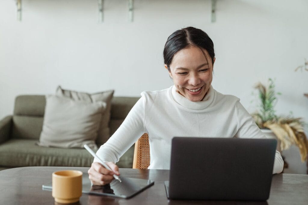 woman sitting at desk working on her laptop and tablet.