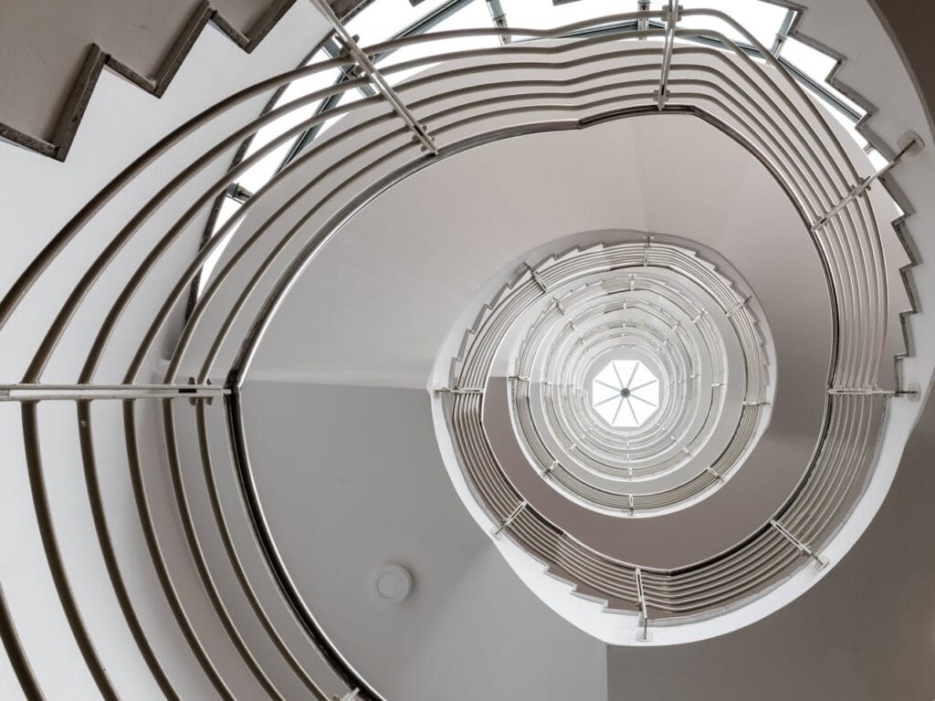 Spiral staircase viewed from above, symbolizing cyclical growth and upward movement.