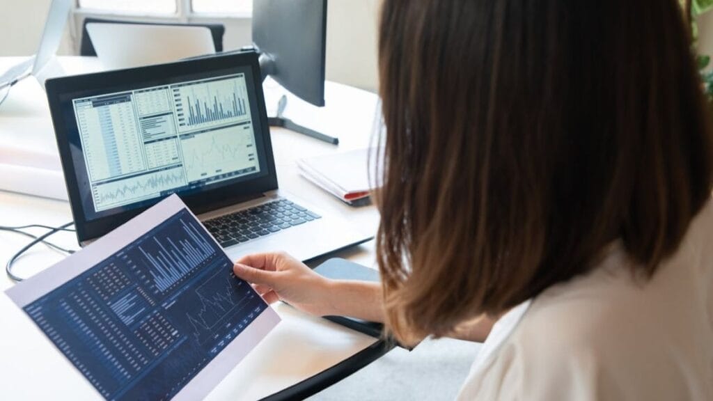 woman holding a printout of report from her laptop.