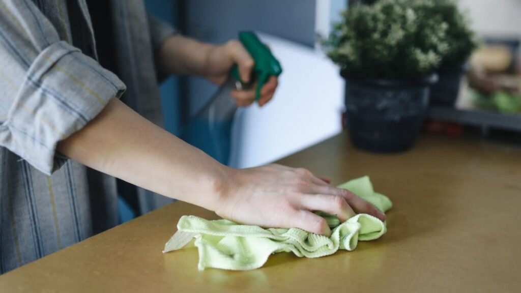 person cleaning the high-use table surface as part of their effective home cleaning routines