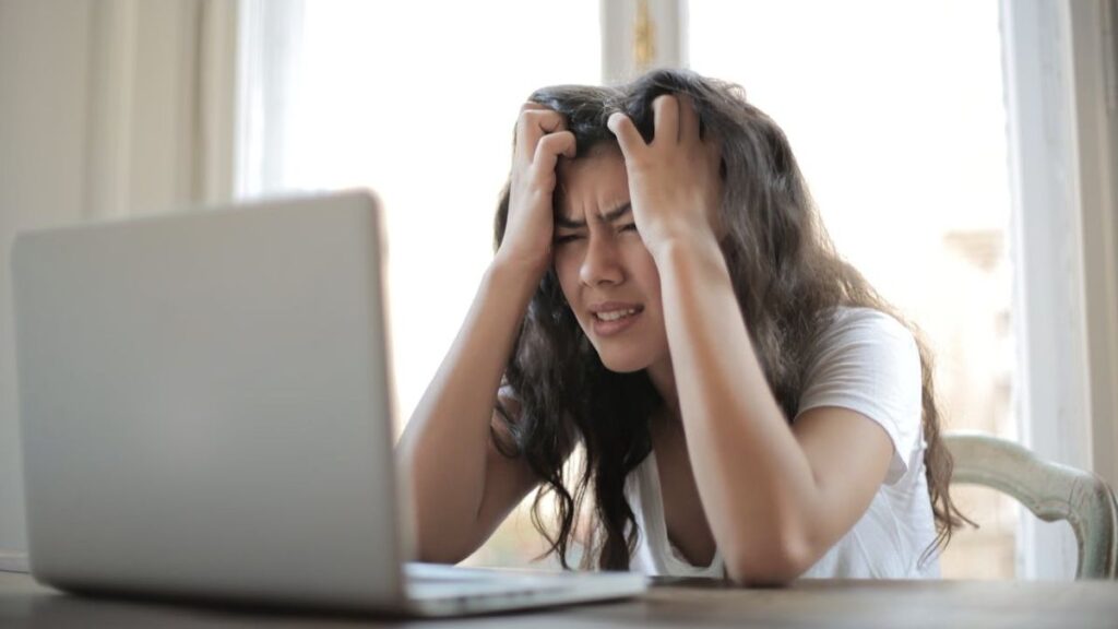 woman distressed about online scams viewing screen of her laptop