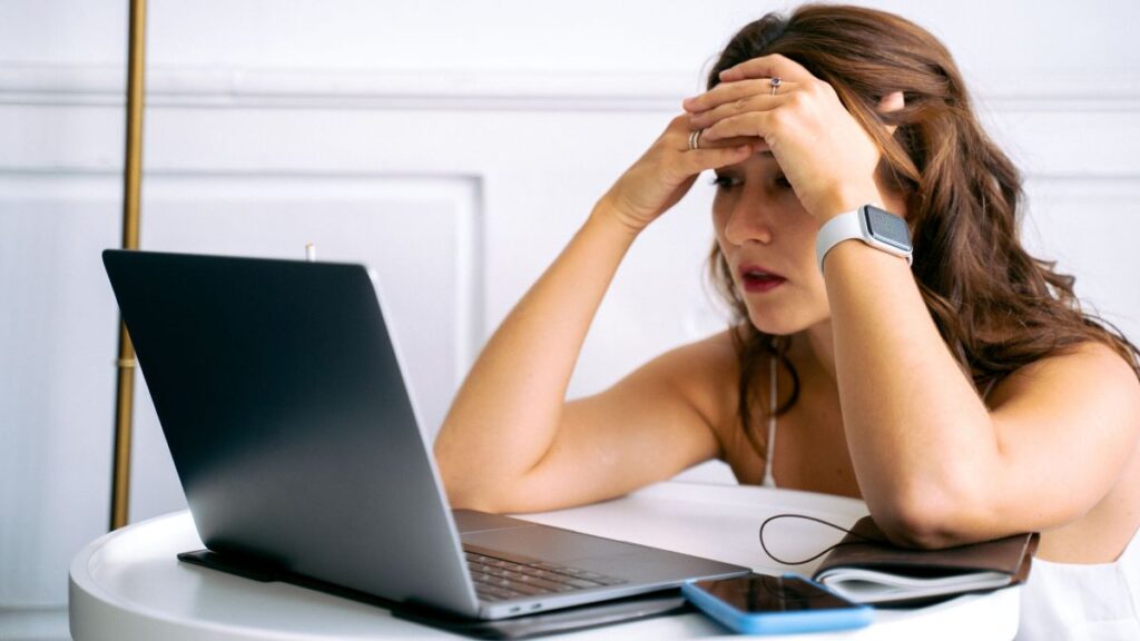 Woman feeling stressed while working on a laptop